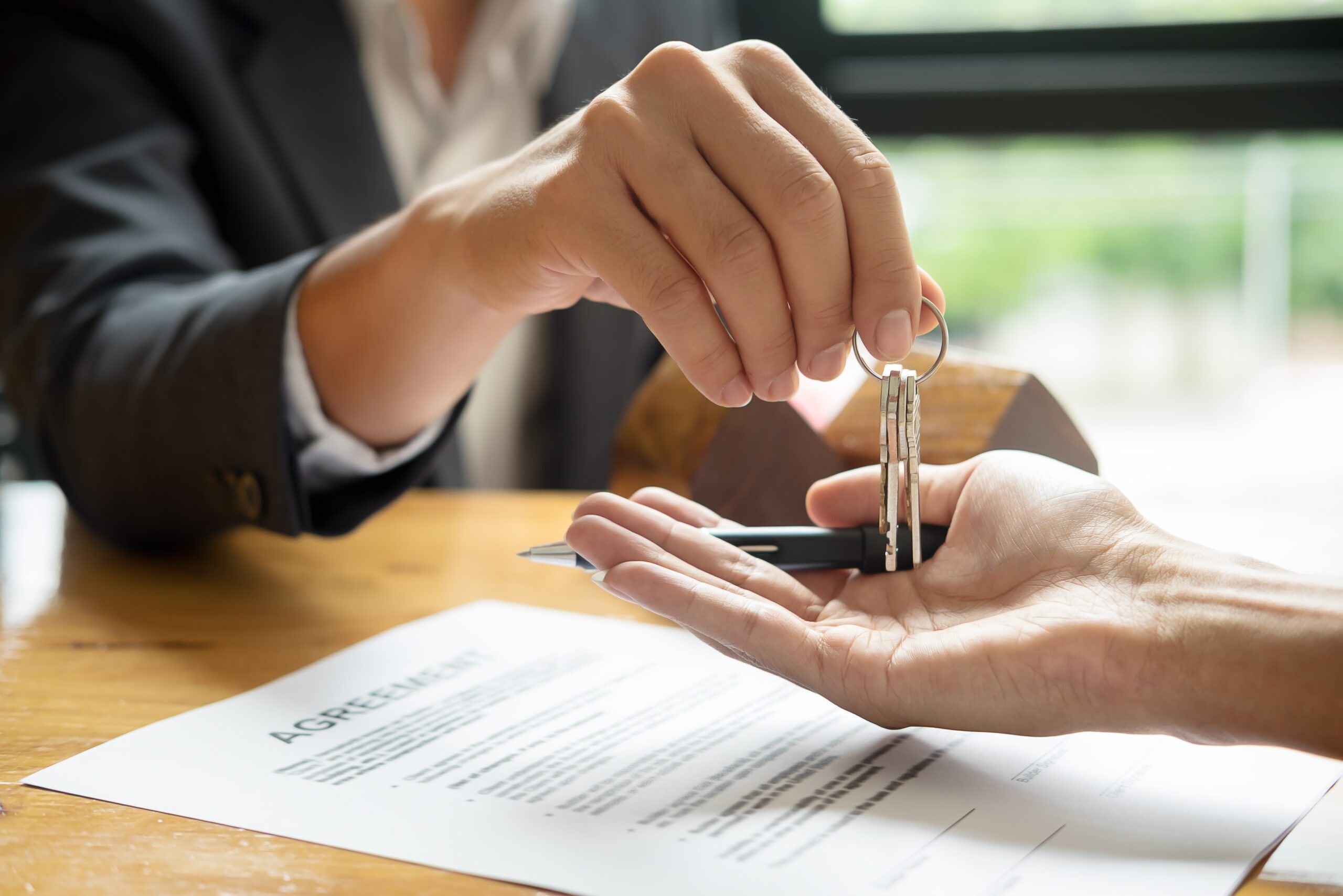 Real Estate Agent Holding House Key To His Client After Signing Contract